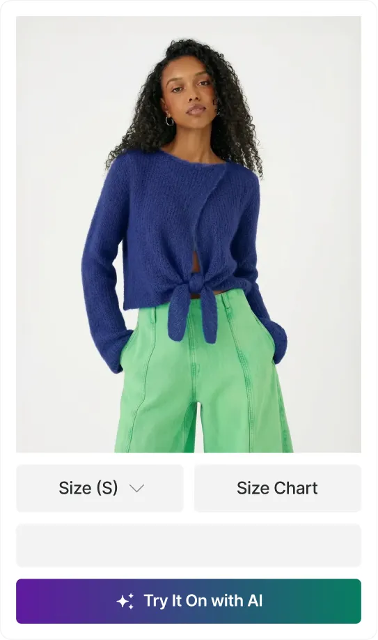 Woman with curly hair wearing a blue tie-front sweater and high-waisted green pants.